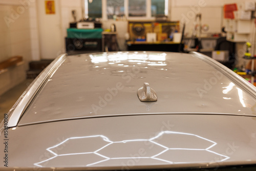 A photo of paintless dent removal glue pucks repairing hail damage of the silver car in the car service.