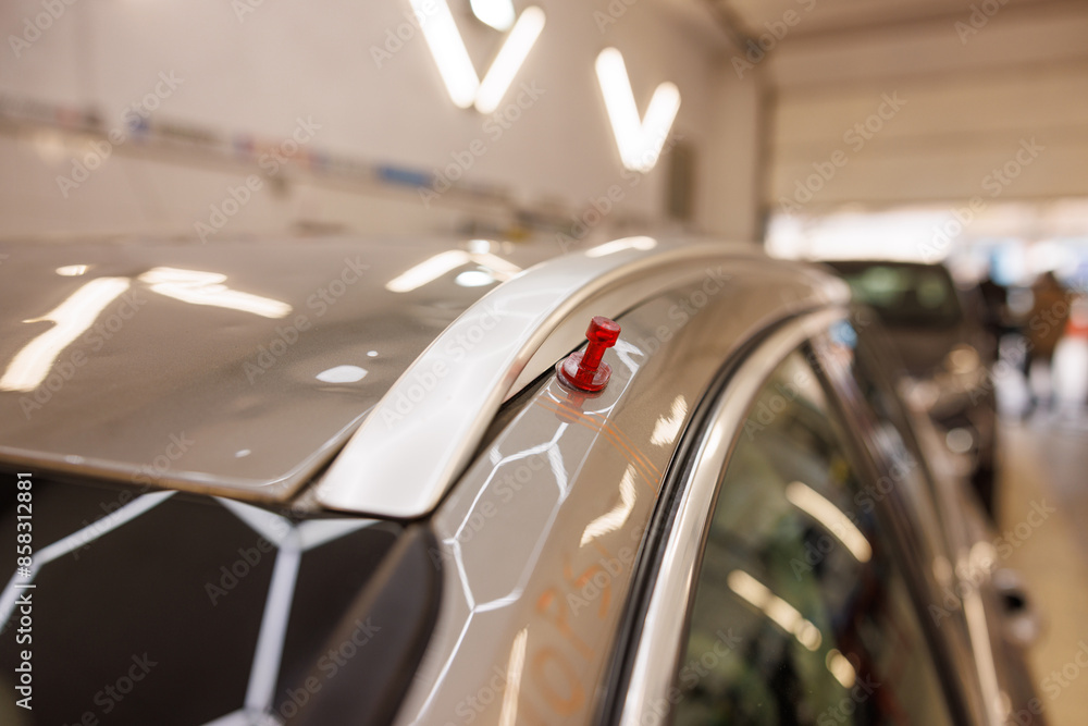 Closeup of a car roof in a garage showcasing automotive damage after hail