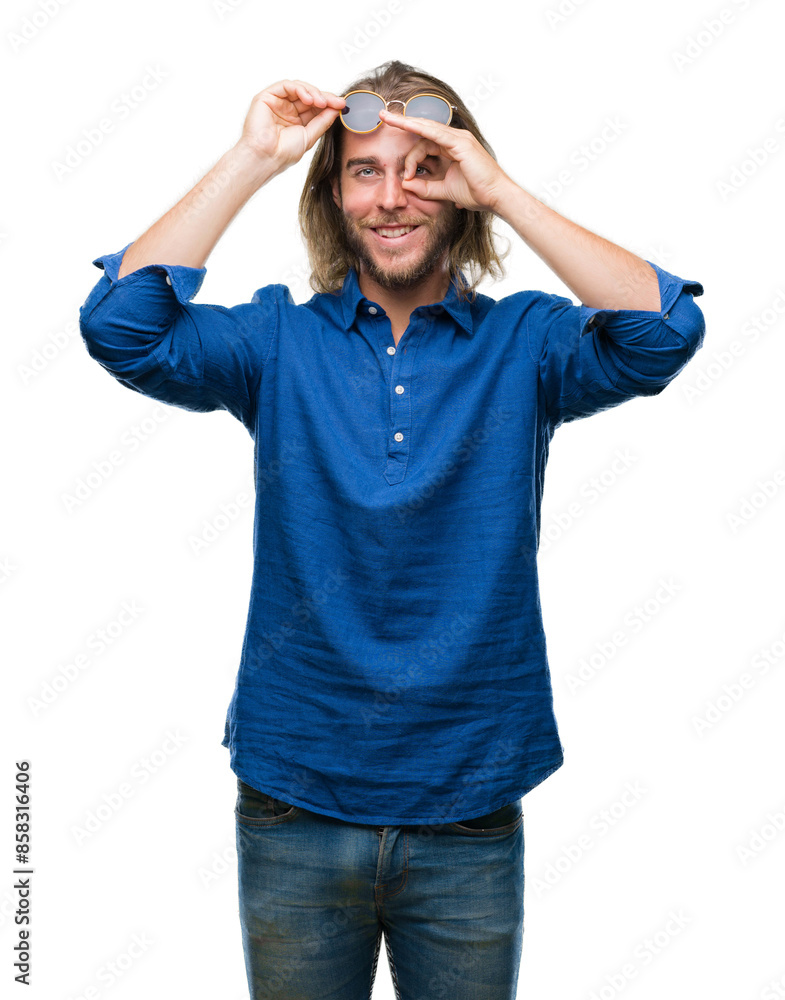 Naklejka premium Young handsome man with long hair wearing sunglasses over isolated background doing ok gesture with hand smiling, eye looking through fingers with happy face.