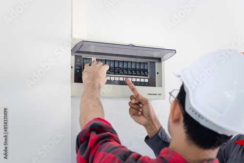 Resetting tripped breaker in residential electricity power control panel in homes and buildings. Men electrician turning off power for electrical outlet at circuit breaker box.