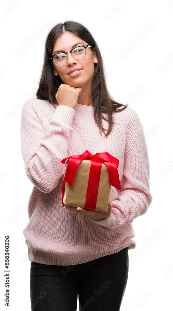 Young hispanic woman holding a gift serious face thinking about question, very confused idea Young hispanic woman holding a gift serious face thinking about question, very confused idea