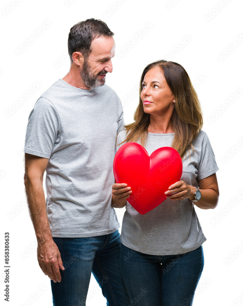 Middle age hispanic casual couple in love holding red heart over isolated background with a confident expression on smart face thinking serious Middle age hispanic casual couple in love holding red heart over isolated background with a confident expression on smart face thinking serious