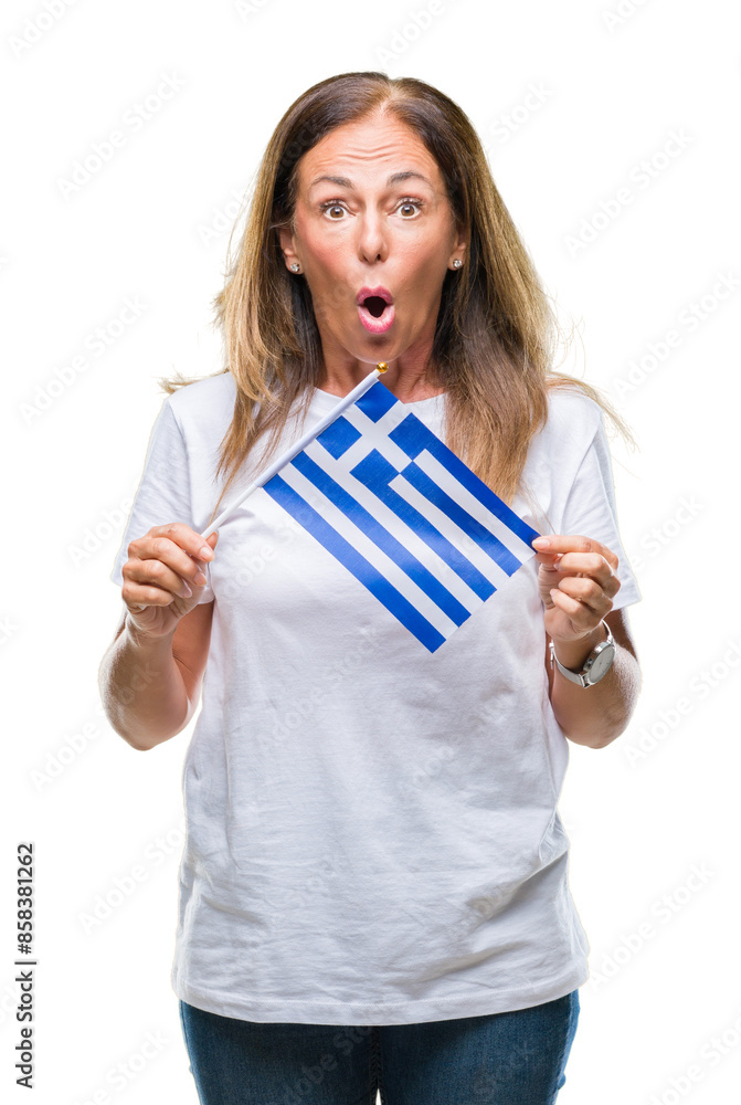 Middle age hispanic woman holding flag of Greece over isolated background scared in shock with a surprise face, afraid and excited with fear expression Middle age hispanic woman holding flag of Greece over isolated background scared in shock with a surprise face, afraid and excited with fear expression