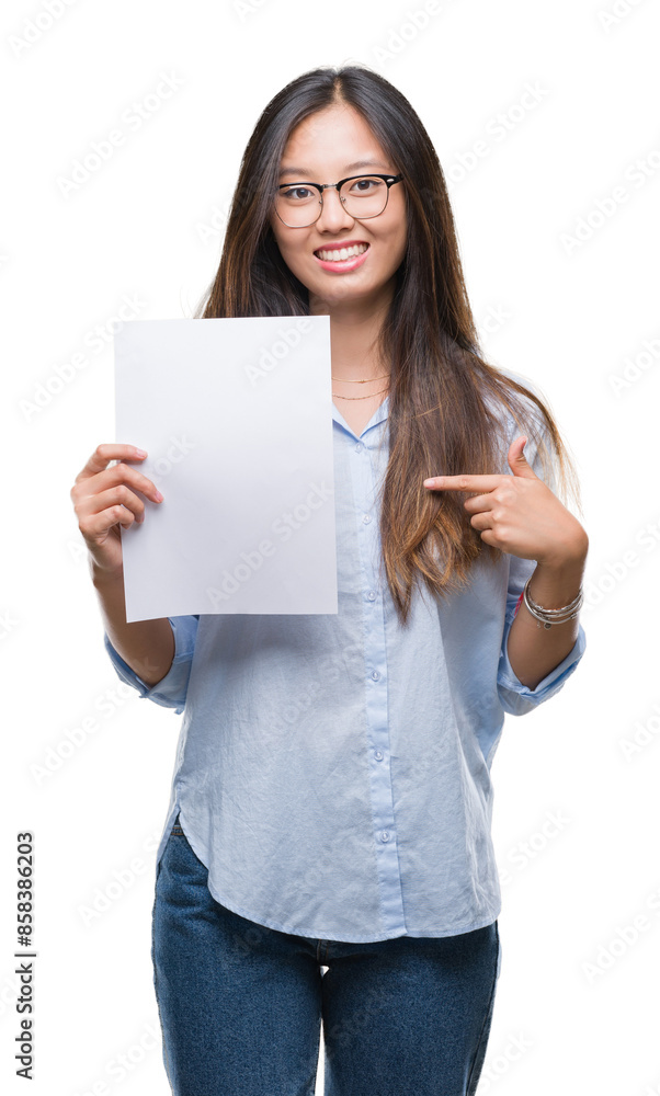 Young asian woman holding blank paper over isolated background with surprise face pointing finger to himself Young asian woman holding blank paper over isolated background with surprise face pointing finger to himself
