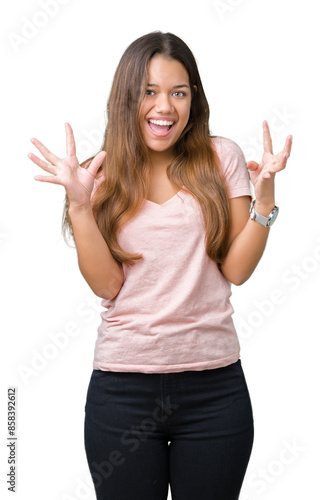 Young beautiful brunette woman wearing pink t-shirt over isolated background celebrating crazy and amazed for success with arms raised and open eyes screaming excited. Winner concept