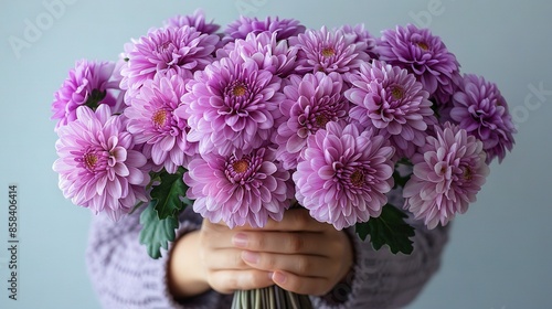 Wallpaper Mural   A close-up of a person holding a bouquet of purple chrysanthemums against a gray backdrop Torontodigital.ca