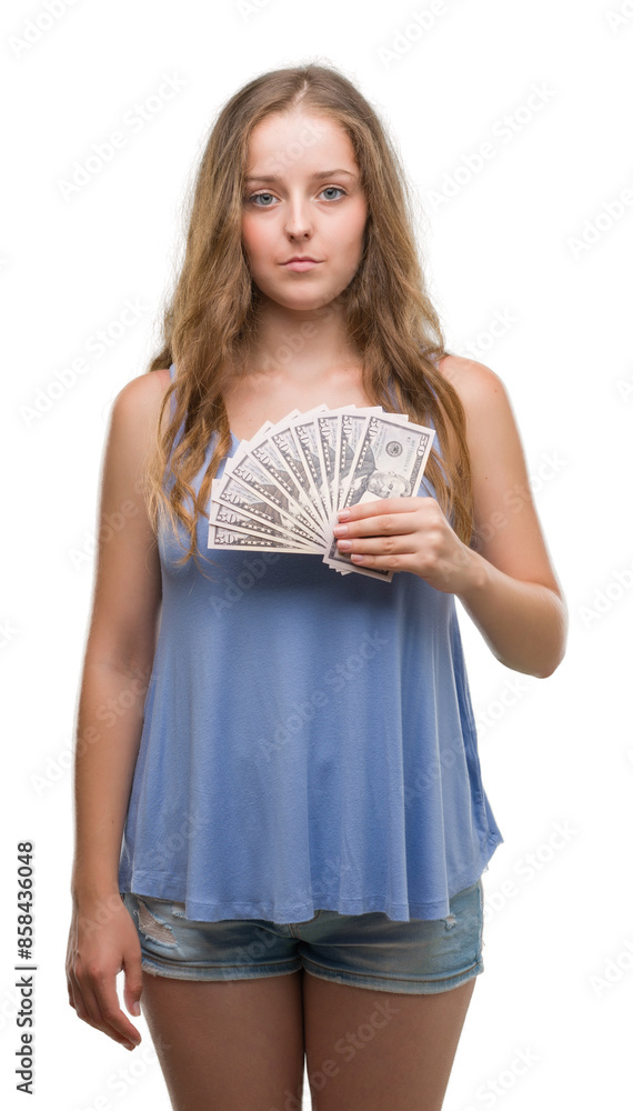 Young blonde woman holding dollars with a confident expression on smart face thinking serious Young blonde woman holding dollars with a confident expression on smart face thinking serious