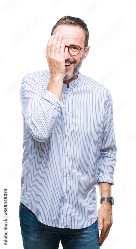 Middle age hoary senior man wearing glasses over isolated background covering one eye with hand with confident smile on face and surprise emotion. Middle age hoary senior man wearing glasses over isolated background covering one eye with hand with confident smile on face and surprise emotion.