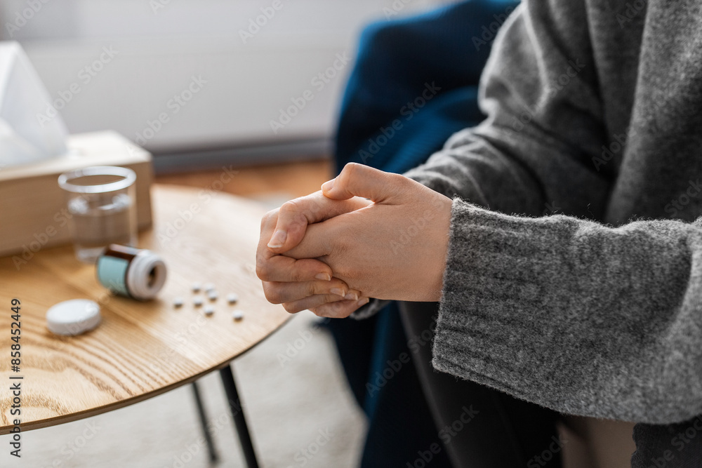 mental health, psychological problem and depression concept - close up of stressed woman hands with sedative medicine or painkiller on table at home