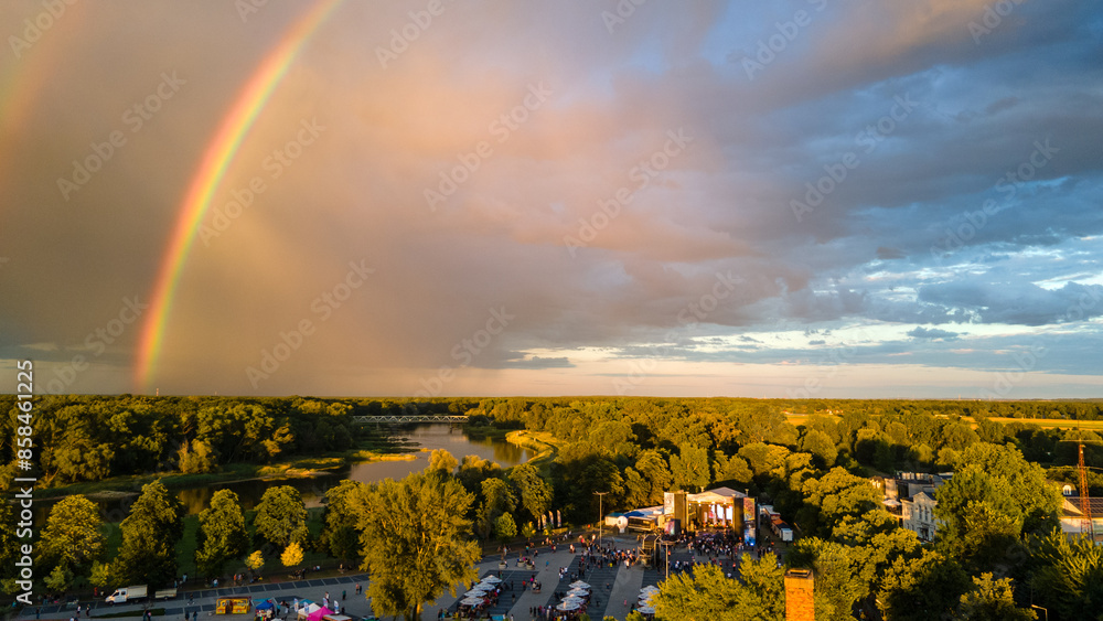 Naklejka premium Widok z lotu ptaka na miasto z tęczą nad miastem i lasem wieczorem