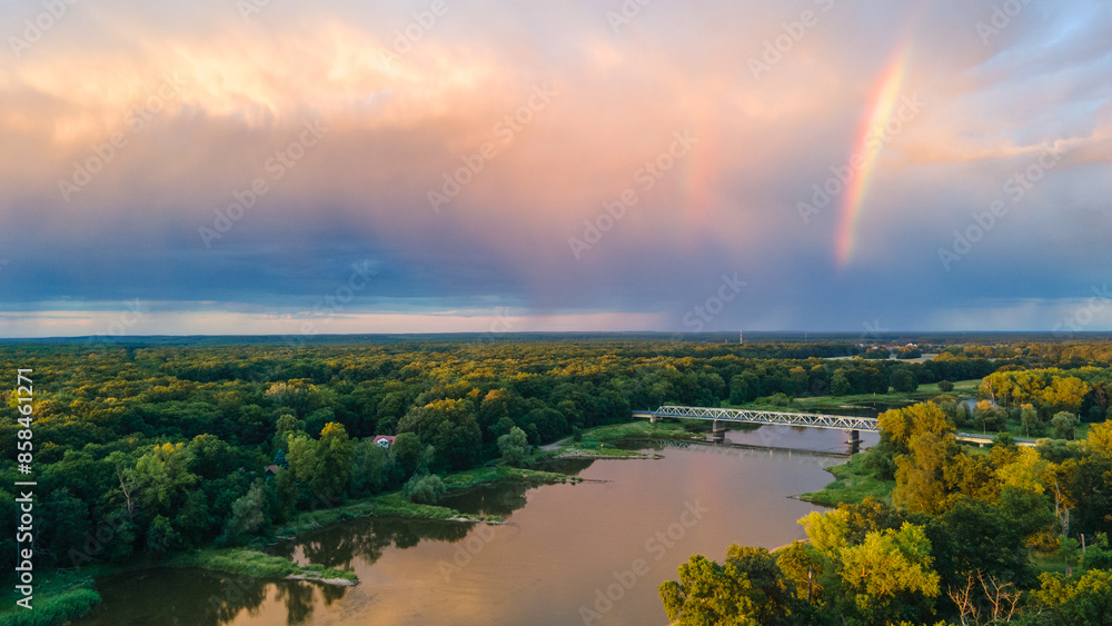 Naklejka premium Widok z lotu ptaka na miasto z tęczą nad miastem i lasem wieczorem