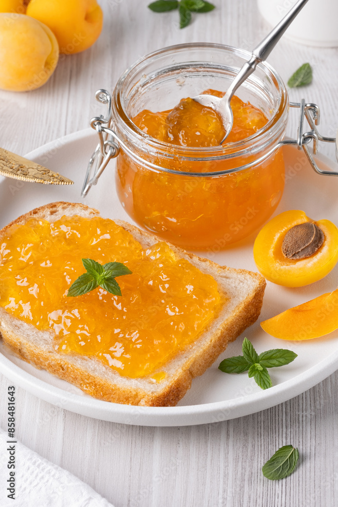 Apricot jam on bread in a white plate and a jar of apricot jam Apricot jam on bread in a white plate and a jar of apricot jam