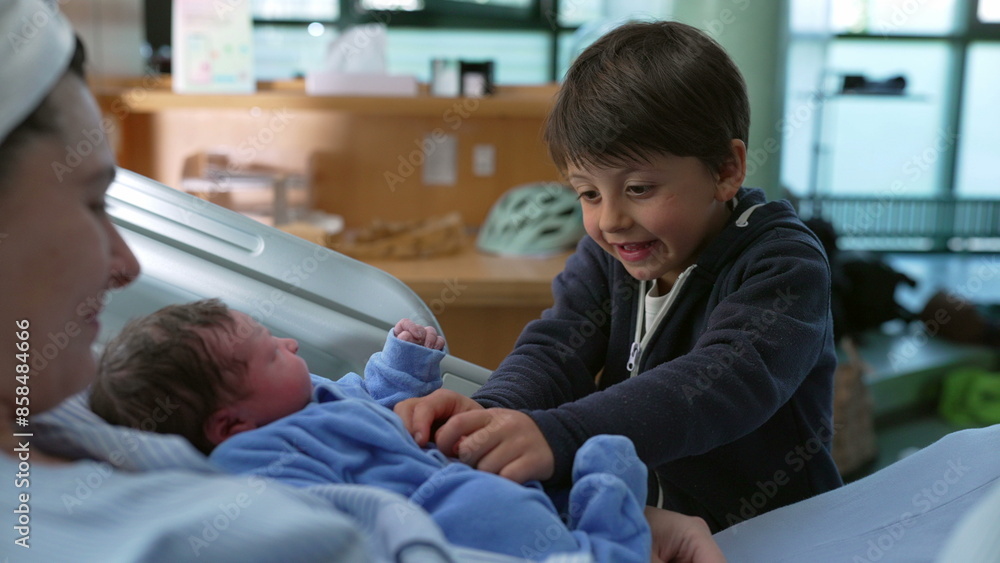 Bonding family moment of sibling interacting with his newborn baby brother at hospital after childbirth while mother watches laid in bed, young boy tickling infant Bonding family moment of sibling interacting with his newborn baby brother at hospital after childbirth while mother watches laid in bed, young boy tickling infant