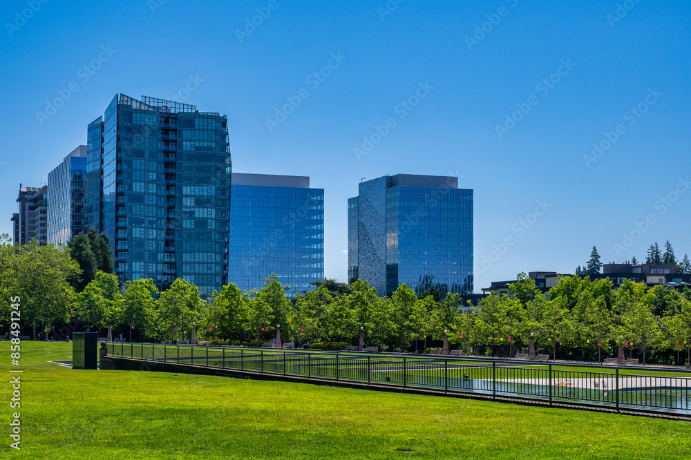 2024-06-21 DOWNTOWN BELLEVUE CITY HALL PARK WITH DOWNTOWN BUILDINGS AT THE SOUTHERN END OF THE PARK WITH THE PARKS POND AND A CLEAR BLUE SKY 2024-06-21 DOWNTOWN BELLEVUE CITY HALL PARK WITH DOWNTOWN BUILDINGS AT THE SOUTHERN END OF THE PARK WITH THE PARKS POND AND A CLEAR BLUE SKY