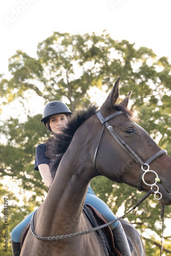 Young equestrian girl woman with horse equine in english tack and riding attire hunter jumper