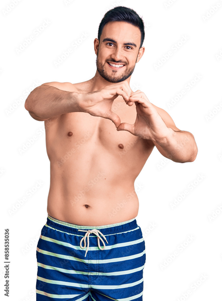 Fototapeta premium Young handsome man wearing swimwear smiling in love doing heart symbol shape with hands. romantic concept.