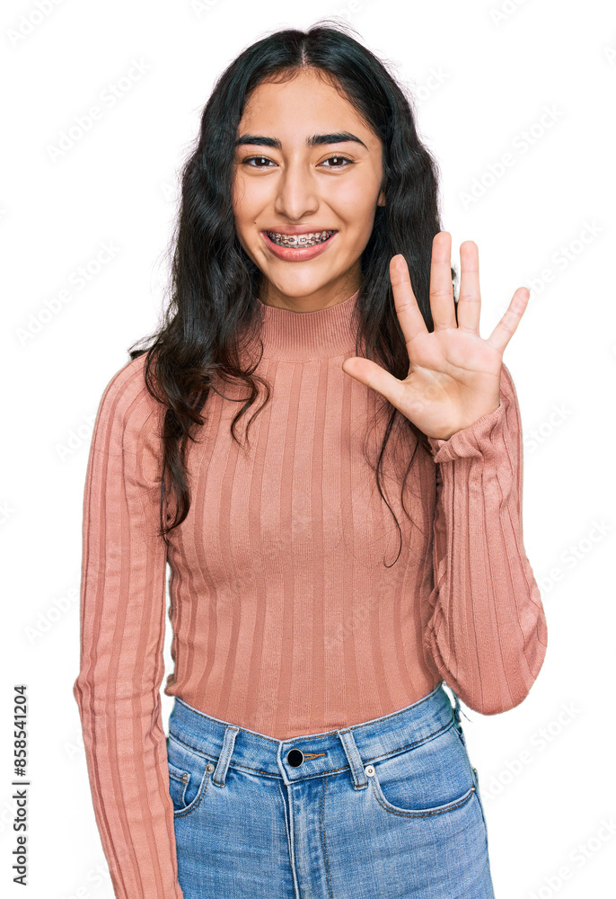 Hispanic teenager girl with dental braces wearing casual clothes showing and pointing up with fingers number five while smiling confident and happy. Hispanic teenager girl with dental braces wearing casual clothes showing and pointing up with fingers number five while smiling confident and happy.