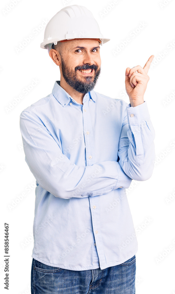 Young handsome man wearing architect hardhat with a big smile on face, pointing with hand and finger to the side looking at the camera. Young handsome man wearing architect hardhat with a big smile on face, pointing with hand and finger to the side looking at the camera.