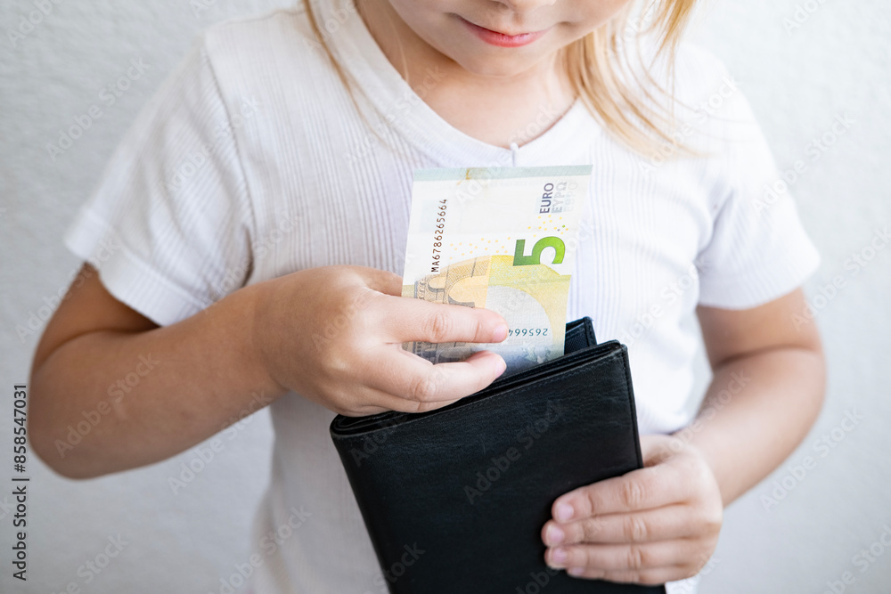 child holds black wallet in hand, kid, girl secretly takes money out of parents' wallet, pulls out euro banknotes, concept of pocket money, Personal Boundaries and Trust, Teaching Financial Literacy child holds black wallet in hand, kid, girl secretly takes money out of parents' wallet, pulls out euro banknotes, concept of pocket money, Personal Boundaries and Trust, Teaching Financial Literacy