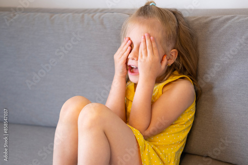 Foto angry blonde girl in soft blurred video covers eyes with hands during tantrum, T