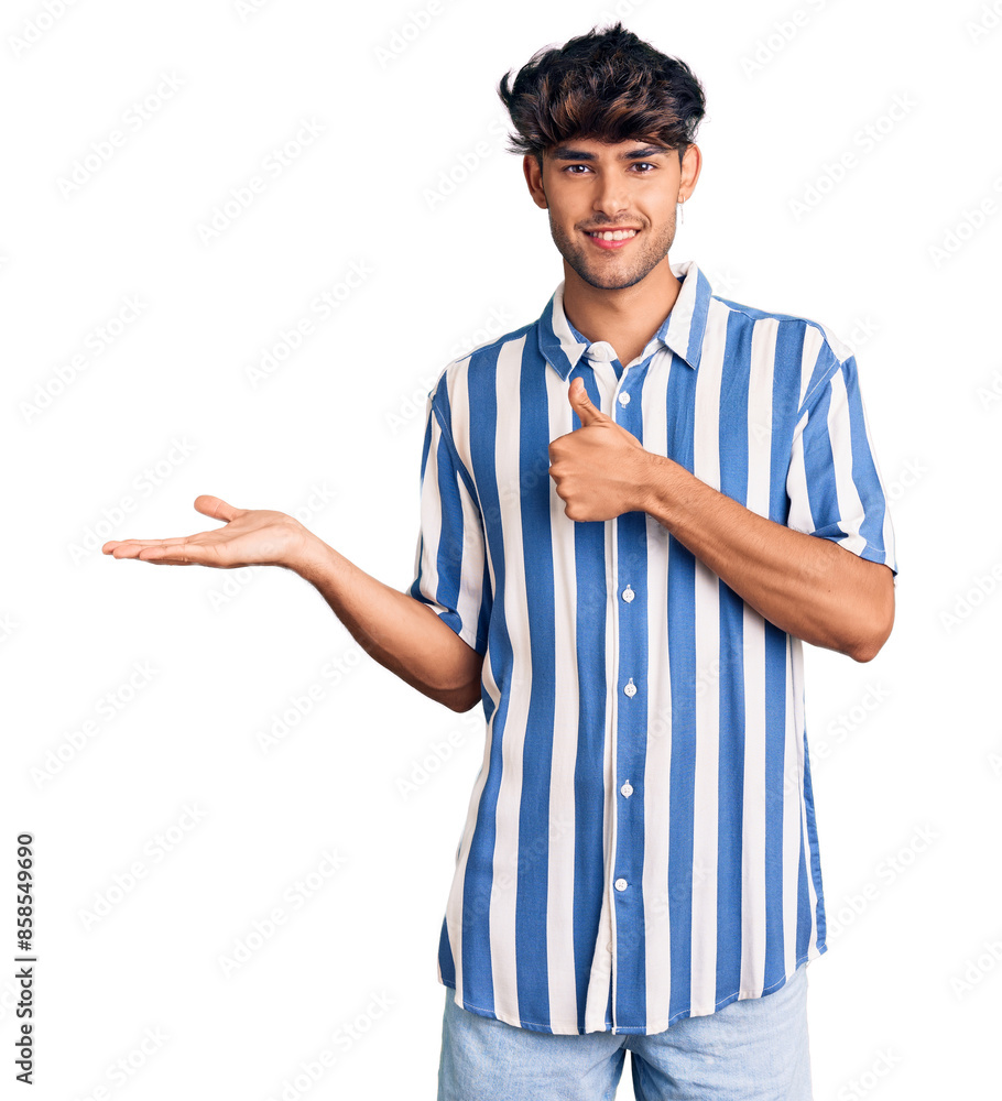 Young hispanic man wearing casual clothes showing palm hand and doing ok gesture with thumbs up, smiling happy and cheerful Young hispanic man wearing casual clothes showing palm hand and doing ok gesture with thumbs up, smiling happy and cheerful