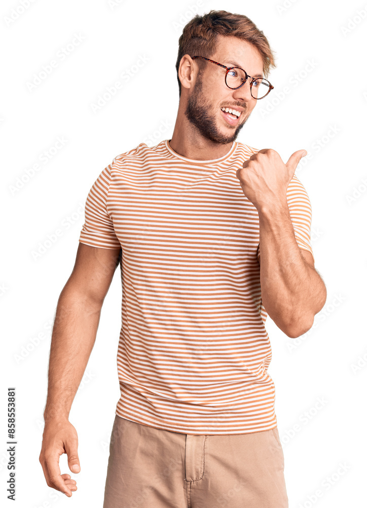 Young caucasian man wearing casual clothes and glasses smiling with happy face looking and pointing to the side with thumb up. Young caucasian man wearing casual clothes and glasses smiling with happy face looking and pointing to the side with thumb up.