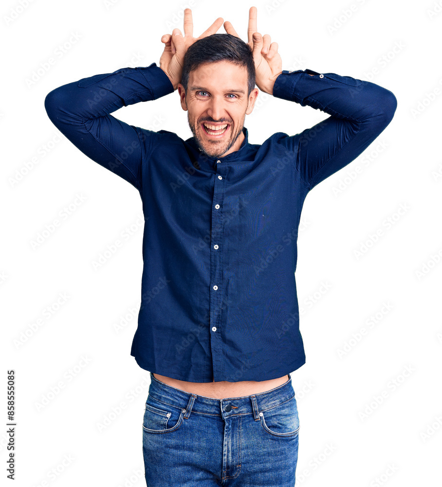 Young handsome man wearing casual shirt posing funny and crazy with fingers on head as bunny ears, smiling cheerful Young handsome man wearing casual shirt posing funny and crazy with fingers on head as bunny ears, smiling cheerful