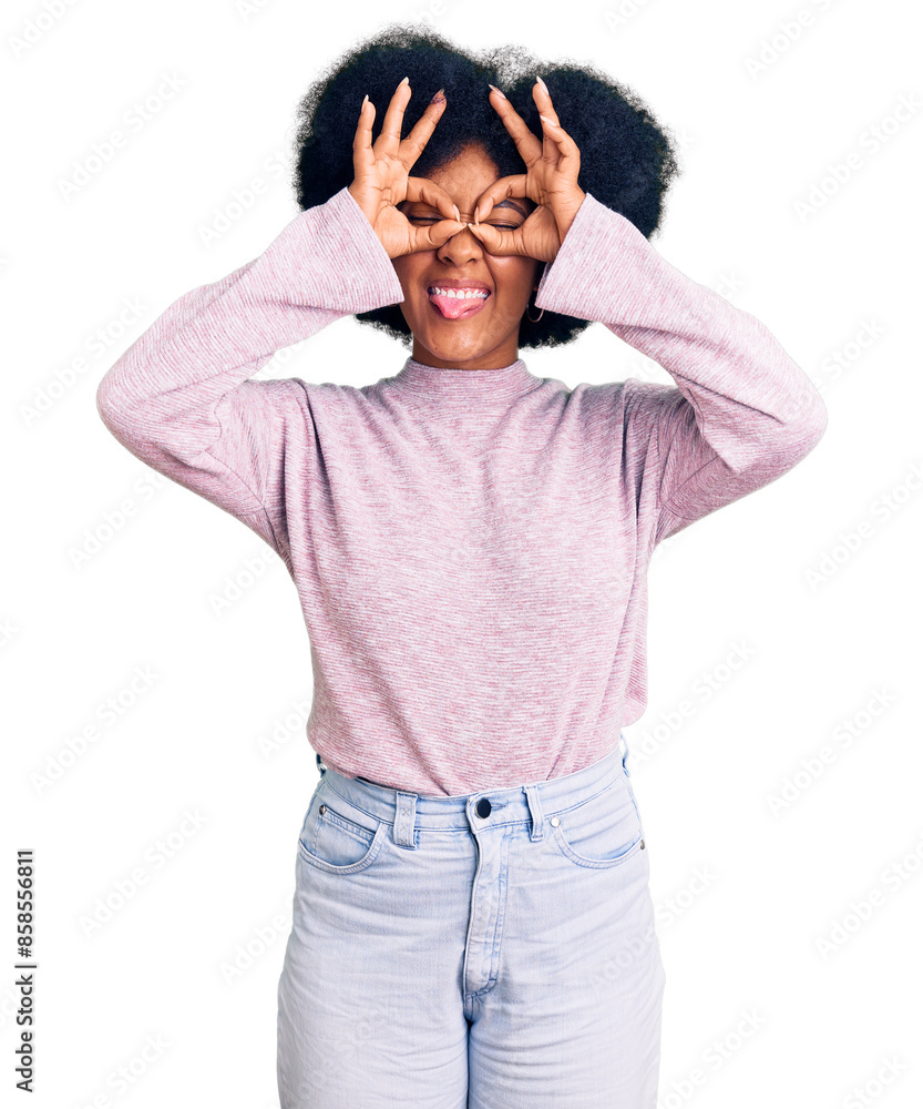 Young african american girl wearing casual clothes doing ok gesture like binoculars sticking tongue out, eyes looking through fingers. crazy expression.