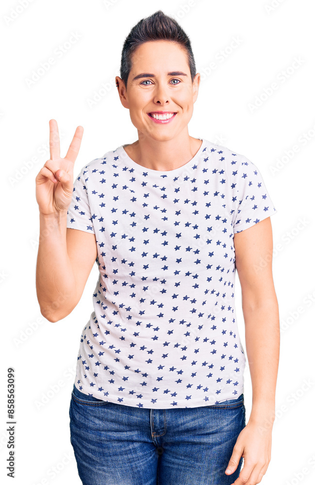 Young woman with short hair wearing casual clothes smiling with happy face winking at the camera doing victory sign. number two. Young woman with short hair wearing casual clothes smiling with happy face winking at the camera doing victory sign. number two.