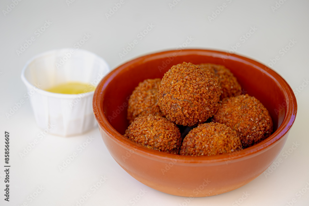 Bitterballen, Dutch meat-based snack in brown bowl served with yellow mustard on the tabel background, Typically containing a mixture of beef or veal, Bitterball are one of Holland's favorite snacks. Bitterballen, Dutch meat-based snack in brown bowl served with yellow mustard on the tabel background, Typically containing a mixture of beef or veal, Bitterball are one of Holland's favorite snacks.