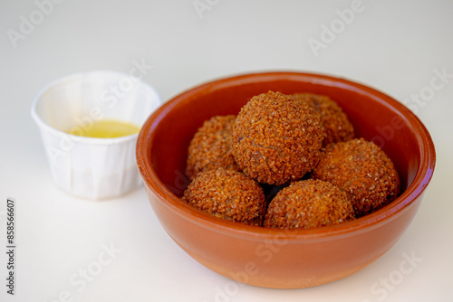 Bitterballen, Dutch meat-based snack in brown bowl served with yellow mustard on the tabel background, Typically containing a mixture of beef or veal, Bitterball are one of Holland's favorite snacks. photo
