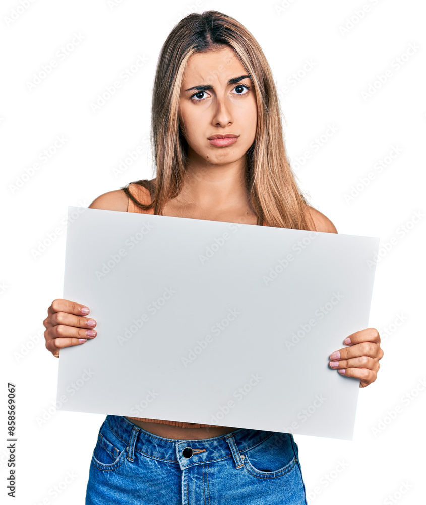Hispanic young woman holding blank empty banner skeptic and nervous, frowning upset because of problem. negative person. Hispanic young woman holding blank empty banner skeptic and nervous, frowning upset because of problem. negative person.