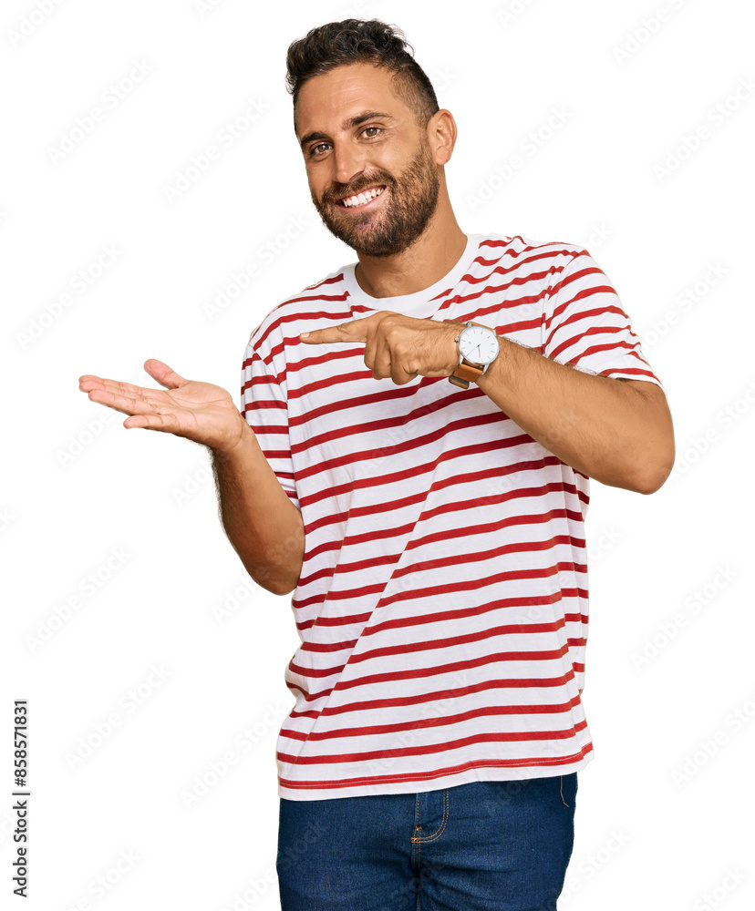 Handsome man with beard wearing striped tshirt amazed and smiling to the camera while presenting with hand and pointing with finger. Handsome man with beard wearing striped tshirt amazed and smiling to the camera while presenting with hand and pointing with finger.