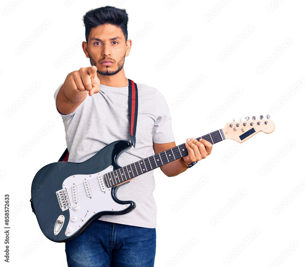 Obraz premium Handsome latin american young man playing electric guitar pointing with finger to the camera and to you, confident gesture looking serious
