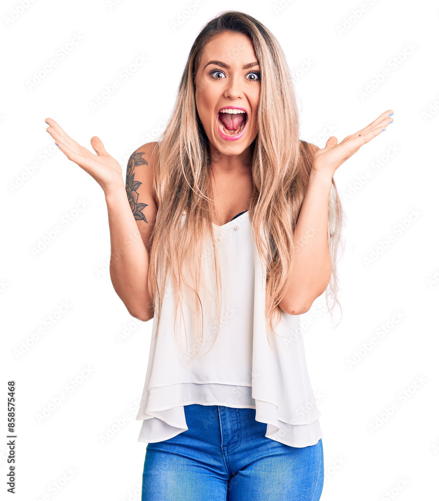 Young beautiful blonde woman wearing sleeveless t-shirt celebrating victory with happy smile and winner expression with raised hands Young beautiful blonde woman wearing sleeveless t-shirt celebrating victory with happy smile and winner expression with raised hands