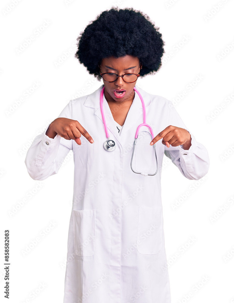Young african american woman wearing doctor coat and stethoscope pointing down with fingers showing advertisement, surprised face and open mouth Young african american woman wearing doctor coat and stethoscope pointing down with fingers showing advertisement, surprised face and open mouth