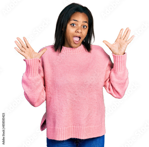 Beautiful hispanic woman wearing casual winter sweater celebrating mad and crazy for success with arms raised and closed eyes screaming excited. winner concept