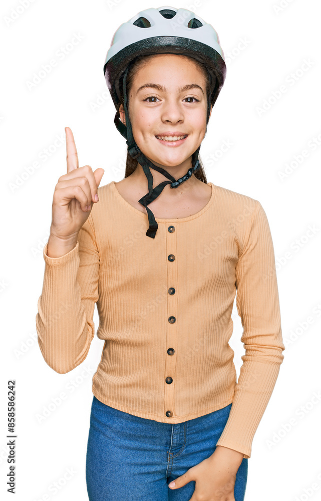 Beautiful brunette little girl wearing bike helmet pointing finger up with successful idea. exited and happy. number one. Beautiful brunette little girl wearing bike helmet pointing finger up with successful idea. exited and happy. number one.