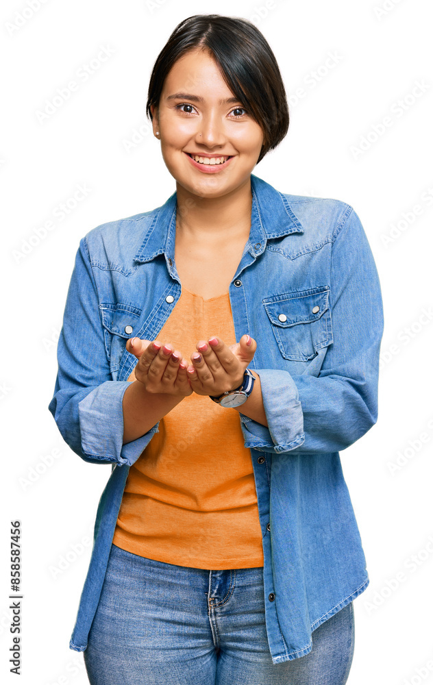 Young beautiful hispanic woman with short hair wearing casual denim jacket smiling with hands palms together receiving or giving gesture. hold and protection Young beautiful hispanic woman with short hair wearing casual denim jacket smiling with hands palms together receiving or giving gesture. hold and protection