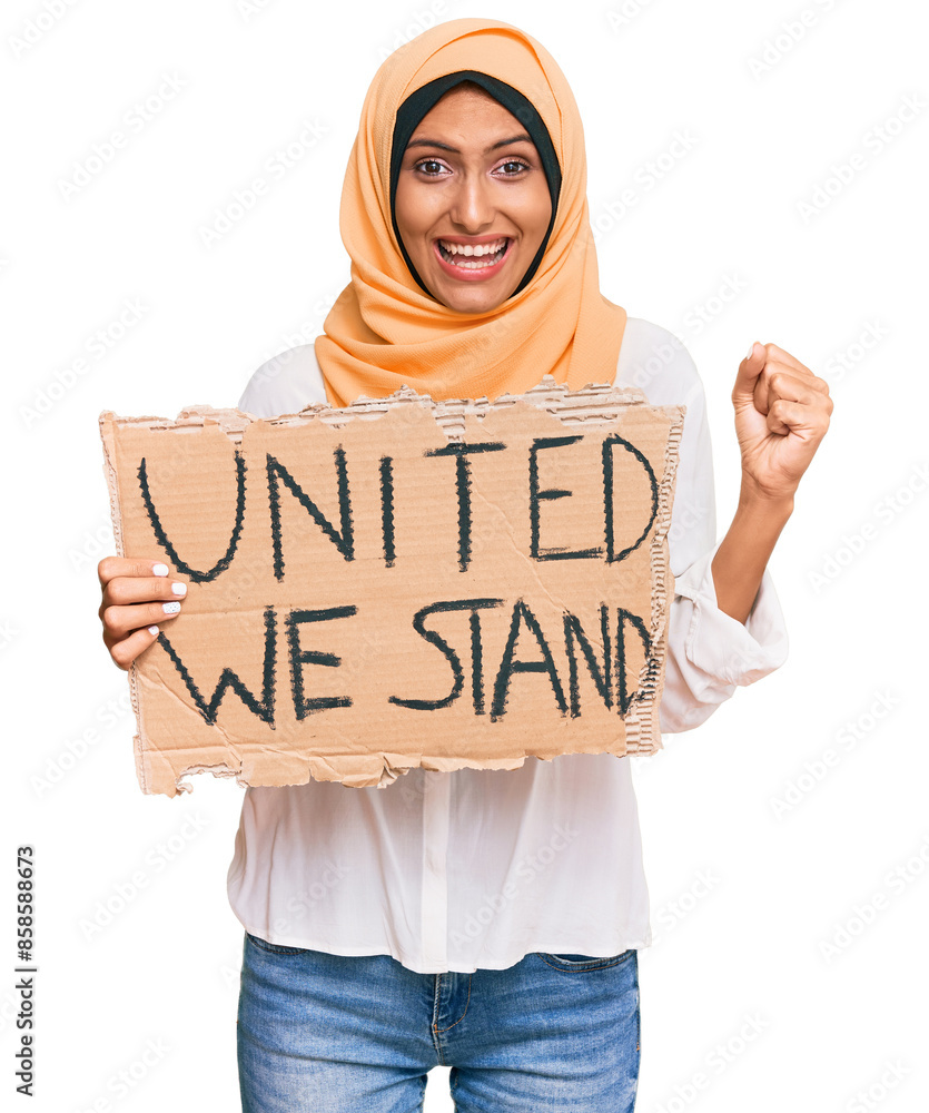 © Krakenimages.com - Young brunette arab woman holding united we stand banner screaming proud, celebrating victory and success very excited with raised arms © Krakenimages.com - Young brunette arab woman holding united we stand banner screaming proud, celebrating victory and success very excited with raised arms