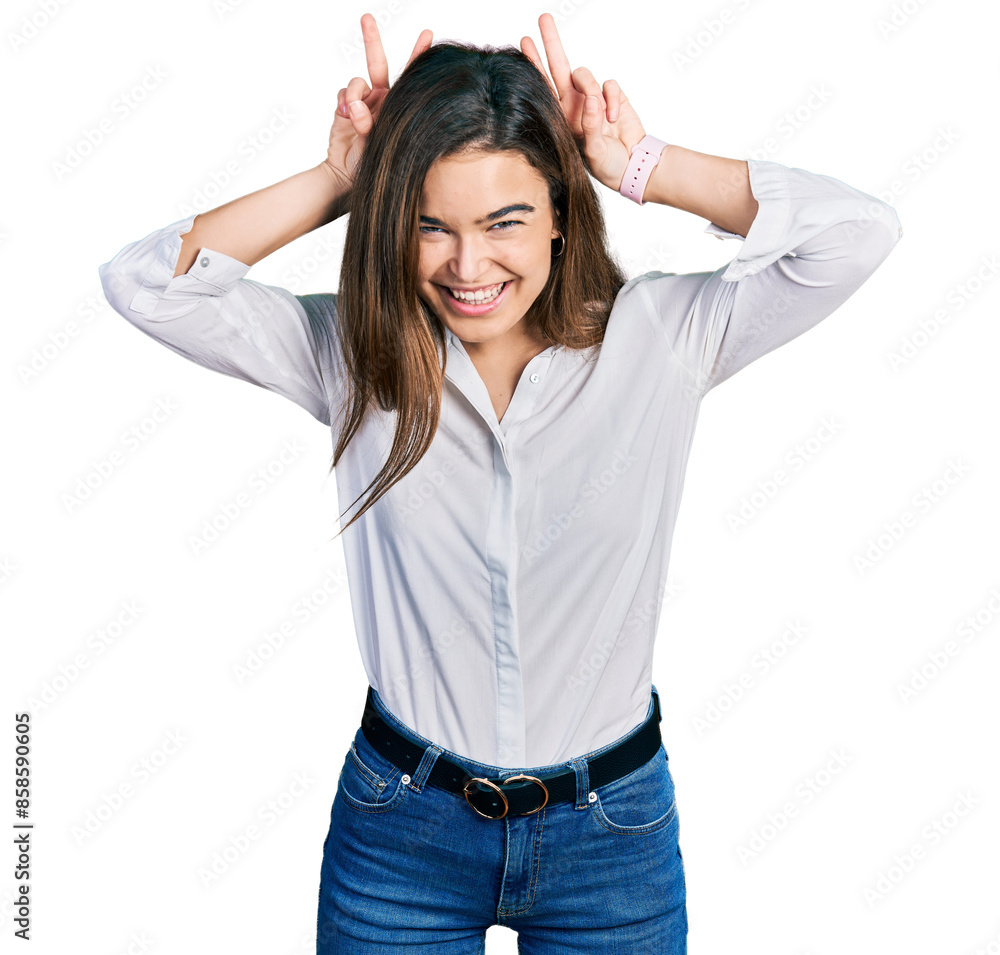 Young caucasian girl wearing casual white shirt posing funny and crazy with fingers on head as bunny ears, smiling cheerful