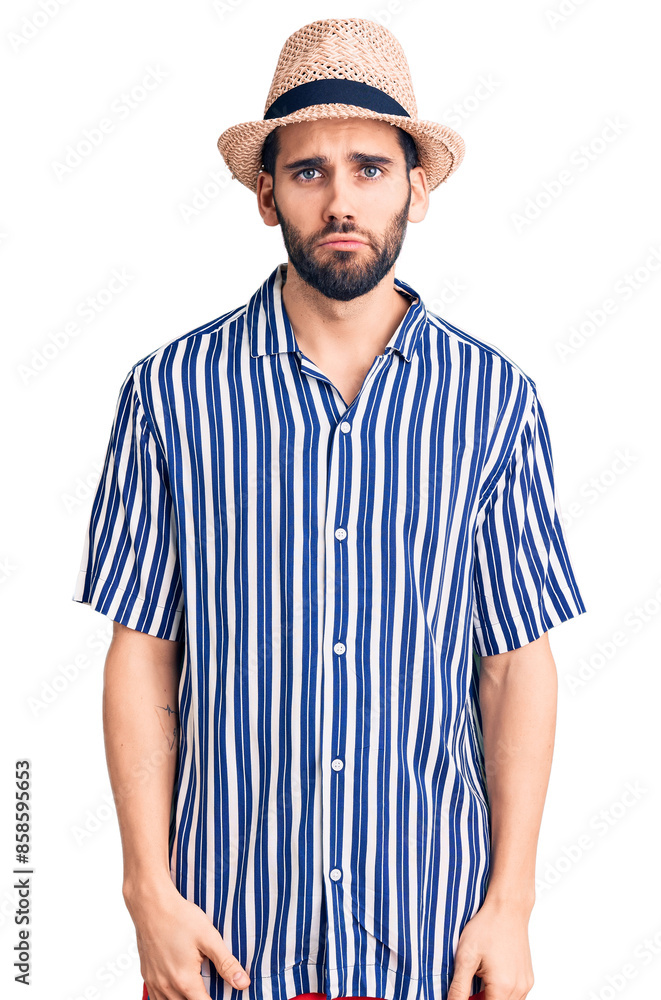 Young handsome man with beard wearing summer hat and striped shirt depressed and worry for distress, crying angry and afraid. sad expression. Young handsome man with beard wearing summer hat and striped shirt depressed and worry for distress, crying angry and afraid. sad expression.