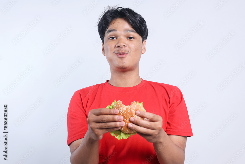 Potrait Of Amazed Young Asian Man Eating Delicious Burger Isolated On White Background Potrait Of Amazed Young Asian Man Eating Delicious Burger Isolated On White Background