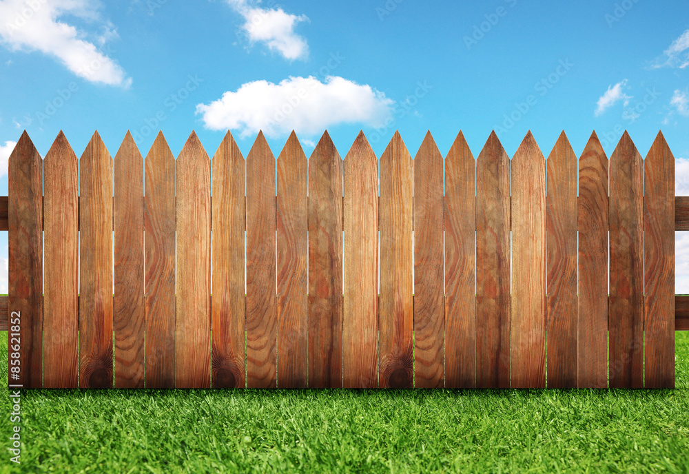 Fototapeta premium Wooden fence and green grass under blue sky with clouds outdoors