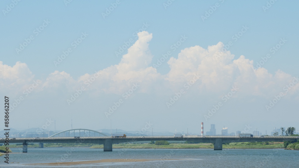Summer blue sky and white clouds. A bridge over a river.