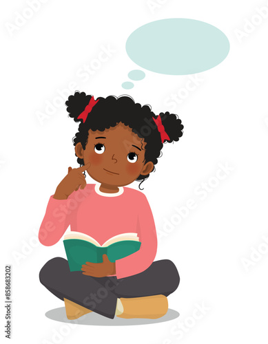 Cute little African girl thinking dreaming while reading book sitting on floor
