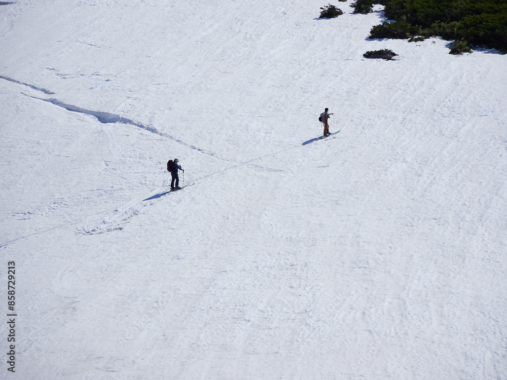 初夏の観光名所立山黒部アルペンルートの室堂の山頂付近の雪山の風景とスキーの観光客の姿 初夏の観光名所立山黒部アルペンルートの室堂の山頂付近の雪山の風景とスキーの観光客の姿