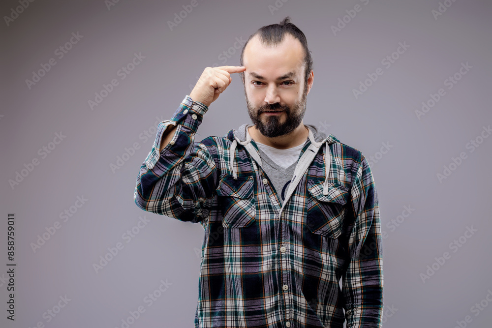 Bearded man pointing to his temple is thinking hard Bearded man pointing to his temple is thinking hard