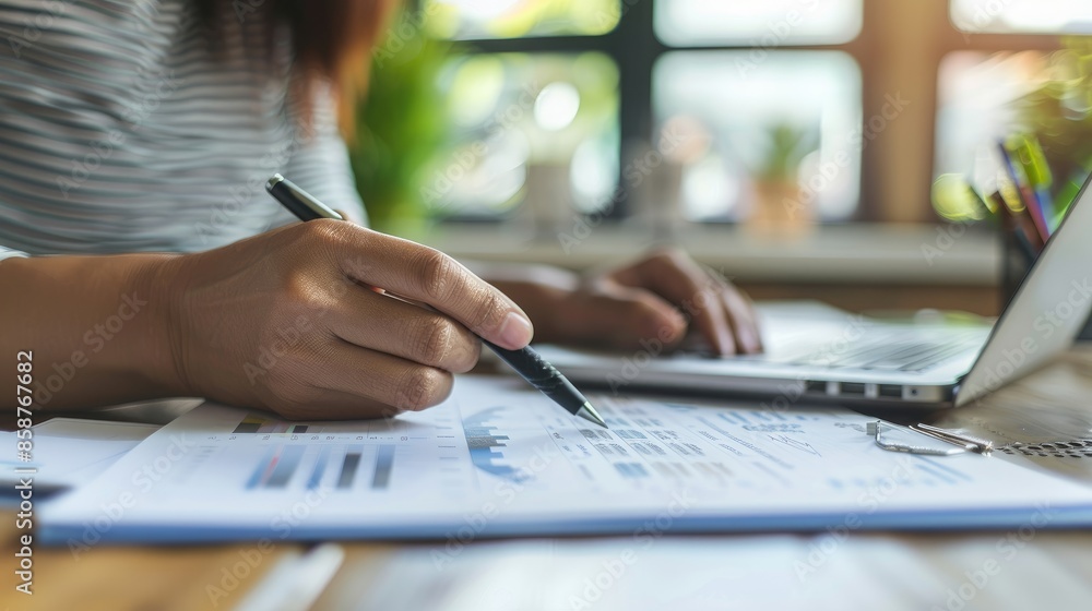 Hands of a business person holding a pen and reviewing documents at a office desk Hands of a business person holding a pen and reviewing documents at a office desk