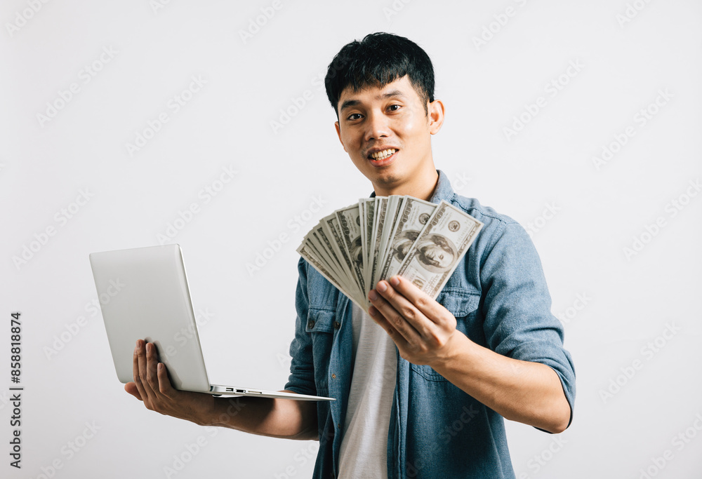 Portrait Asian smiling young man holding laptop computer and fan of money cash studio shot isolated white background, Happy excited lifestyle businessman hold money in dollar banknotes Portrait Asian smiling young man holding laptop computer and fan of money cash studio shot isolated white background, Happy excited lifestyle businessman hold money in dollar banknotes